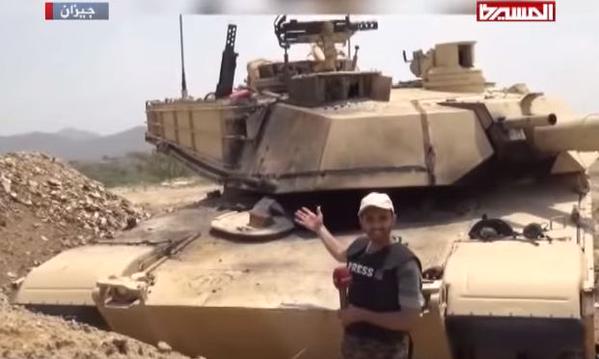 An-Al-Masirah-reporter-and-Houthis-stand-next-to-a-captured-Saudi-M1-Abrams-tank-1.jpg